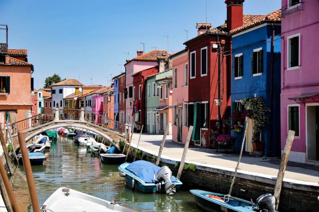 Burano, Italy-Colorful houses line a canal with boats in it