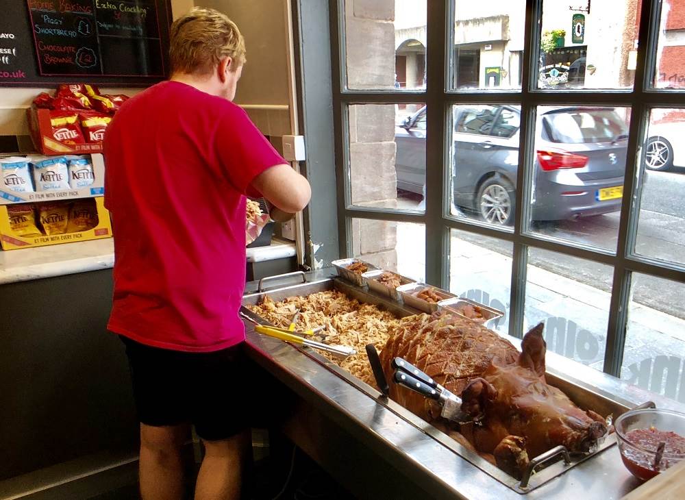 man standing beside a whole roasted pig at Oink in Edinburgh