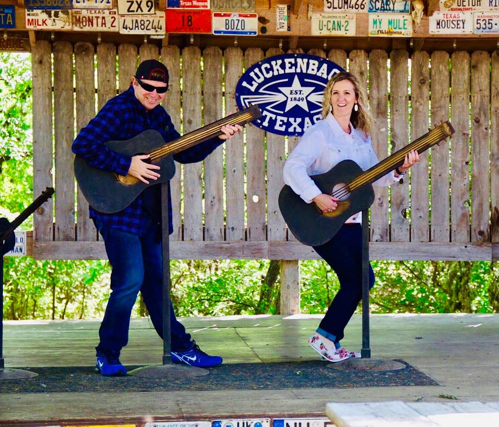 girl and guy playing guitars on the Luckenbach Texas stage
